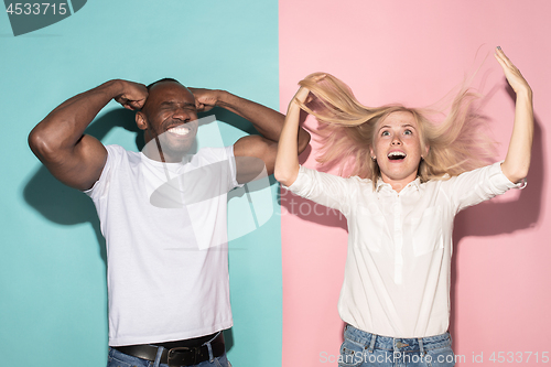 Image of We won. Winning success happy afro man and woman celebrating being a winner. Dynamic image of caucasian female and male model on pink studio.