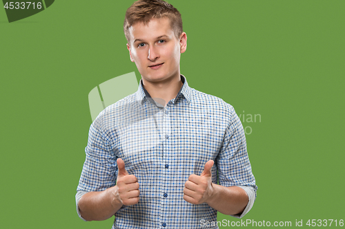 Image of The happy businessman standing and smiling against green background.