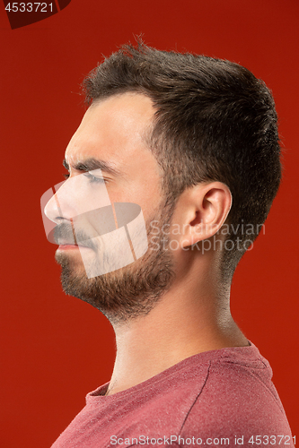 Image of The young emotional angry man screaming on red studio background