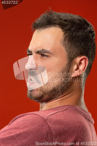 Image of The young emotional angry man screaming on red studio background