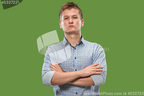 Image of The serious businessman standing and looking at camera against green background.