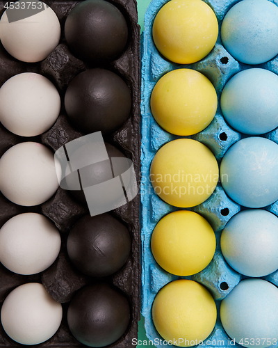 Image of Set of colorful painted yellow, blue, black and white eggs in different cardboard boxes. Easter background. Flat lay