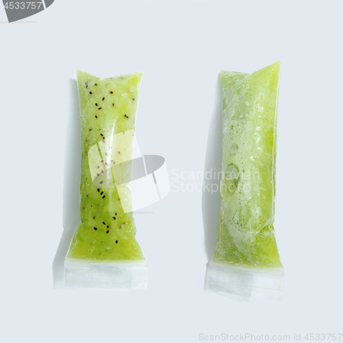 Image of Green kiwi ice cream in vacuum plastic sticks on a gray background with copy space. Top view