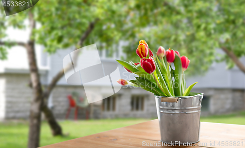 Image of red tulip flowers on table over summer garden