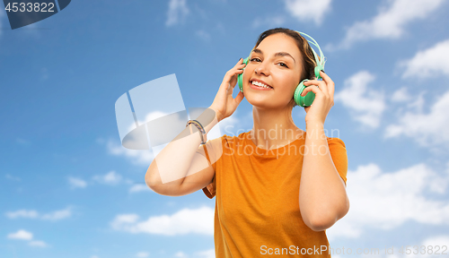 Image of teenage girl in earphones over sky