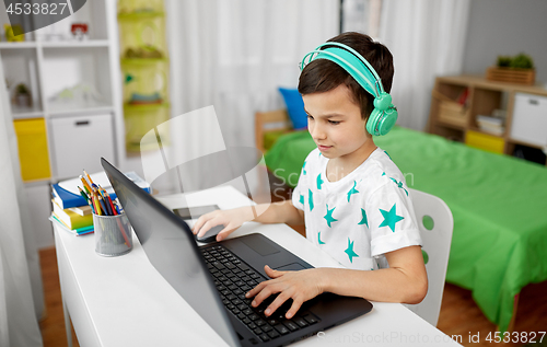 Image of boy in headphones playing video game on laptop