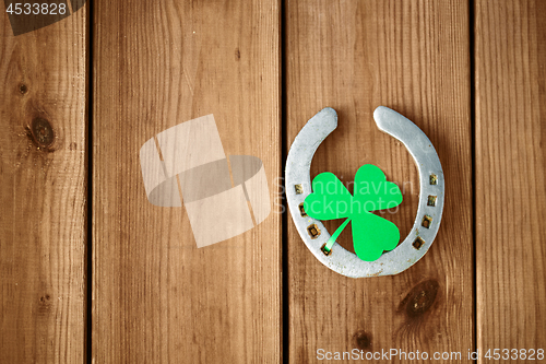 Image of horseshoe with shamrock on wooden background