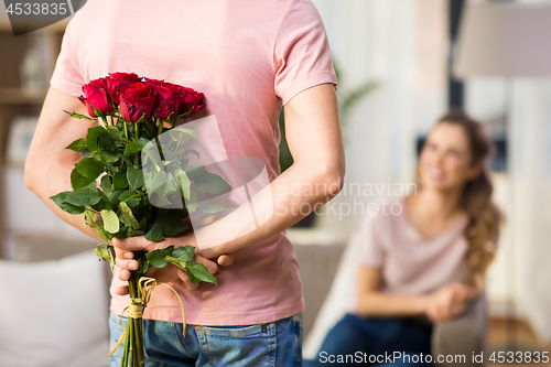 Image of woman and man with bunch of roses behind his back