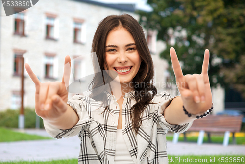 Image of teenage girl showing rock sign over campus