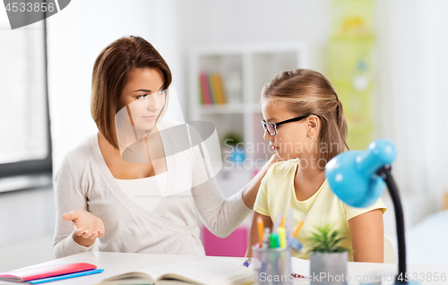 Image of upset mother talking to daughter doing homework