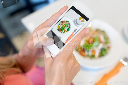 Image of woman with smartphone photographing food at cafe