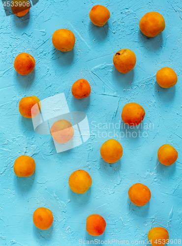 Image of Ripe sweet apricots on a blue background.