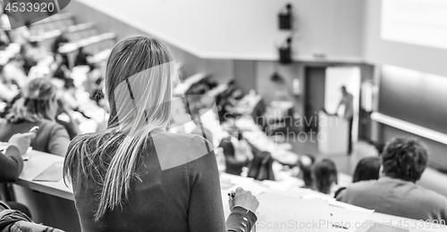 Image of Audience in the lecture hall. Female student making notes.