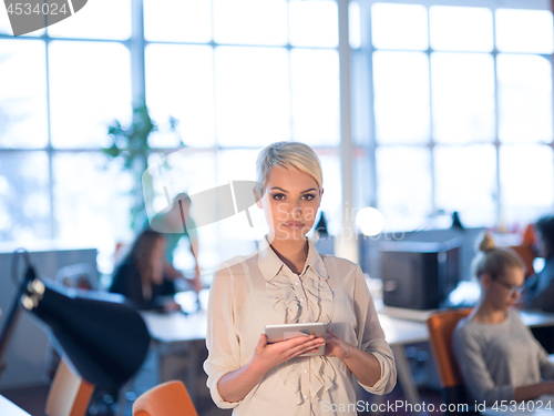 Image of woman working on digital tablet in night office