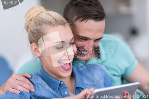 Image of couple relaxing at  home with tablet computers