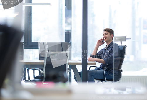 Image of Young casual businessman using smartphone