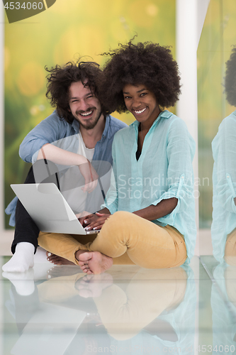 Image of multiethnic couple using a laptop on the floor
