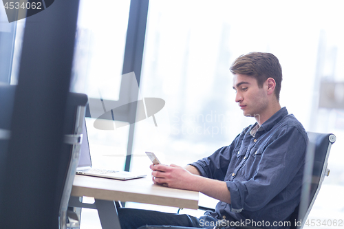 Image of Young casual businessman using smartphone