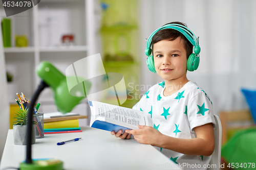 Image of boy in headphones with textbook learning at home