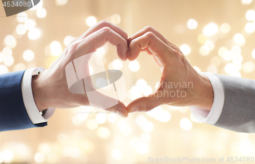 Image of close up of male gay couple making hand heart