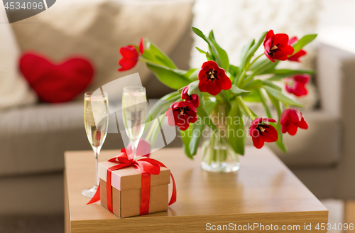 Image of gift box, champagne glasses and flowers on table