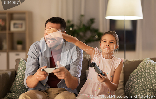 Image of father and daughter playing video game at home