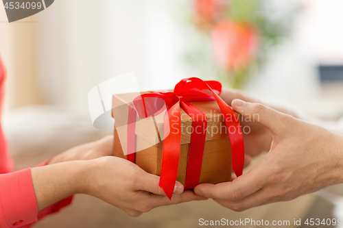 Image of close up of male and female hands with gift box