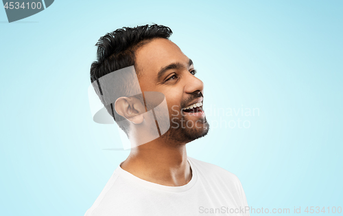 Image of young laughing indian man over gray background