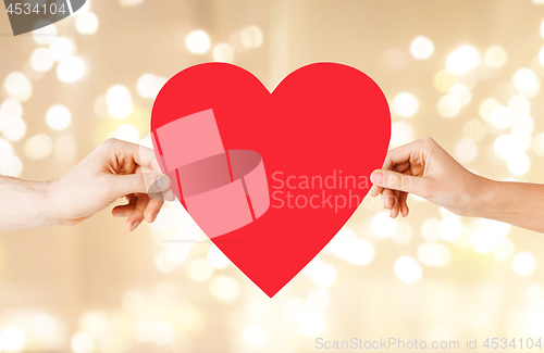 Image of couple hands holding red heart