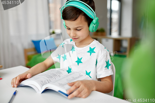 Image of boy in headphones with textbook learning at home