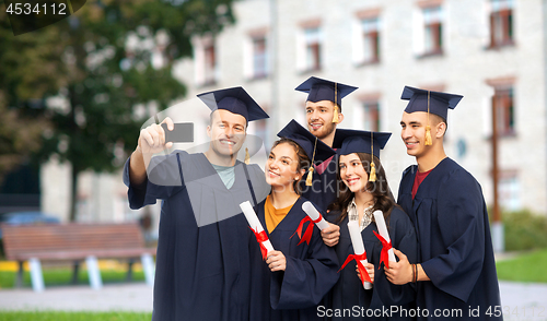 Image of graduates with diplomas taking selfie by cellphone