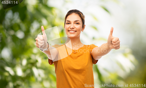 Image of teen girl showing thumbs up over natural backgdrop