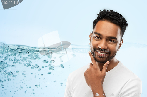 Image of smiling indian man touching his beard