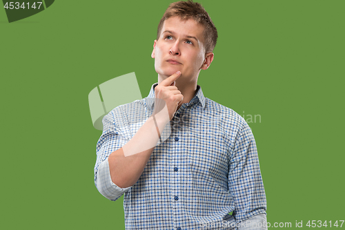 Image of Let me think. Doubtful pensive man with thoughtful expression making choice against green background