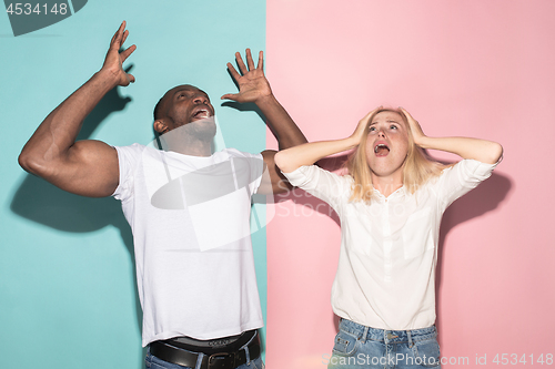 Image of We won. Winning success happy afro man and woman celebrating being a winner. Dynamic image of caucasian female and male model on pink studio.