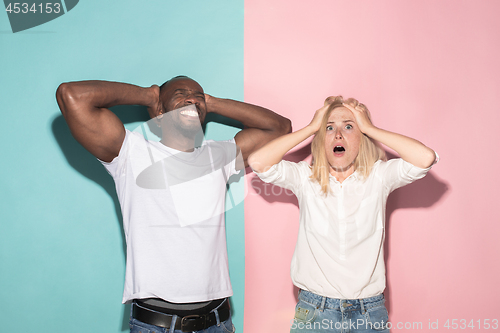 Image of We won. Winning success happy afro man and woman celebrating being a winner. Dynamic image of caucasian female and male model on pink studio.