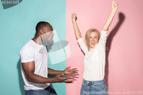 Image of We won. Winning success happy afro man and woman celebrating being a winner. Dynamic image of caucasian female and male model on pink studio.