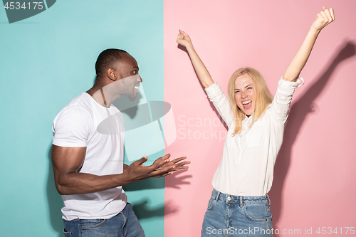 Image of We won. Winning success happy afro man and woman celebrating being a winner. Dynamic image of caucasian female and male model on pink studio.