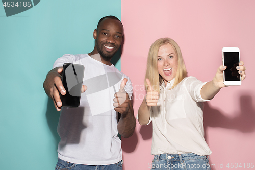 Image of Portrait of a confident casual girl showing blank screen mobile phone and afro man