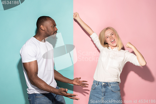 Image of We won. Winning success happy afro man and woman celebrating being a winner. Dynamic image of caucasian female and male model on pink studio.