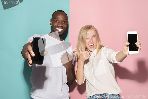 Image of Portrait of a confident casual girl showing blank screen mobile phone and afro man