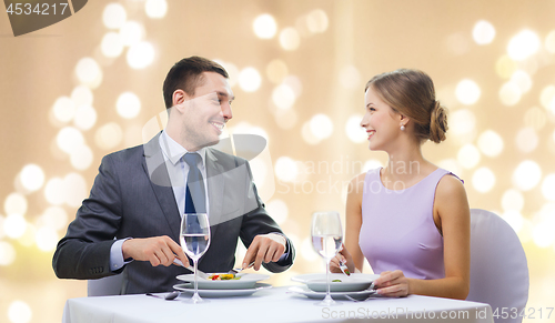 Image of smiling couple eating appetizers at restaurant