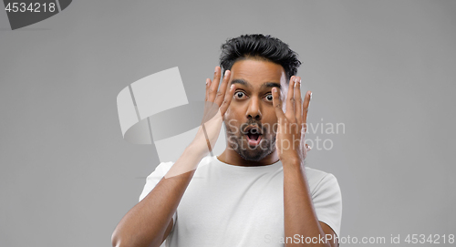 Image of shocked indian man over grey background