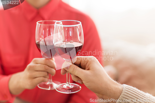 Image of hands of couple clinking red wine glasses