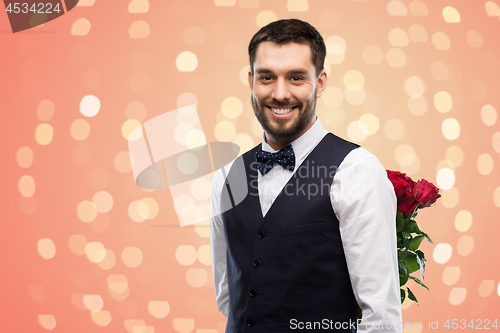 Image of happy man with red roses behind his back