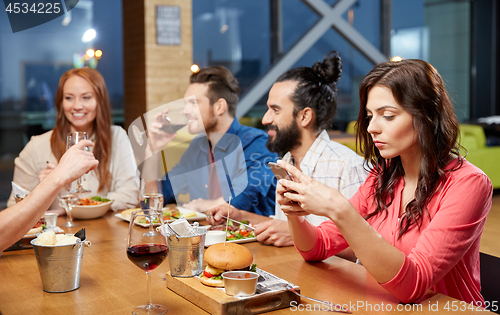 Image of bored woman messaging on smartphone at restaurant