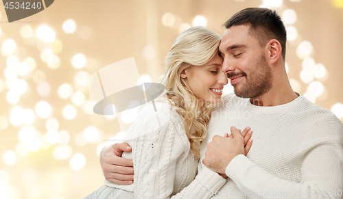 Image of happy couple hugging over lights on background