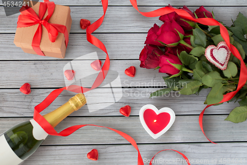 Image of close up of champagne, gift, candies and red roses