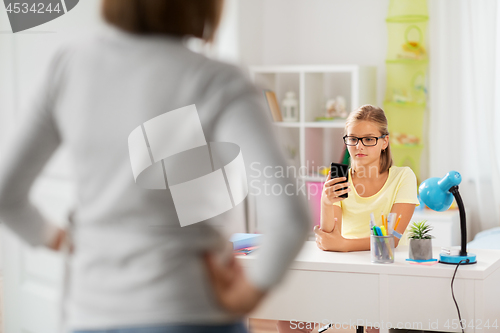 Image of girl with smartphone distracting from homework