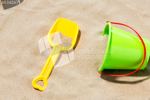 Image of close up of toy bucket and shovel on beach sand